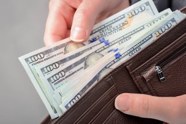 Kadınların elleri onları cüzdanından çıkarırken yüz dolarlık banknotları sayıyor. Düşük açıyla yakın çekim.