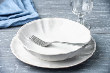 Boş bir tabak, masada çatal, boş bir bardak şarap ve peçeteyle. Stüdyo görüntüsü yüksek açılı..