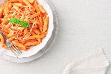 Fotokopi alanı olan keten masa örtüsünün üzerinde fesleğen yapraklı All 'Arrabbiata Penne makarnasının yakın çekimi. Üst görünüm.