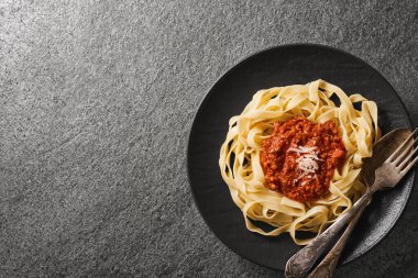 Top view plate of tagliatelle pasta and BOLOGNESE SAUCE with copy space. Gray background from natural stone.