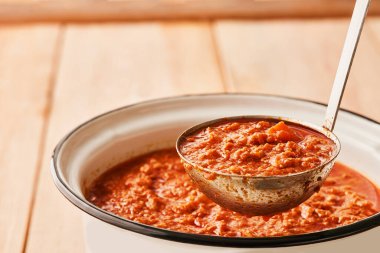 Saucepan and ladle of fresh BOLOGNESE SAUCE on kitchen table with copy space. Low angle view.