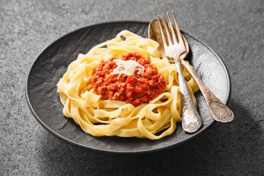 Close-up of a plate of fresh tagliatelle pasta with bolognese sauce on a gray background. High angle view.