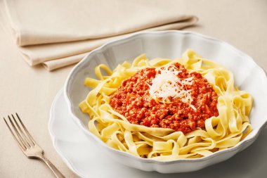 Bir tabak taze tagliatelle makarna ve keten masa örtüsü üzerine BOLOGNESE sosu. Bir nesne. Düşük açı görünümü.