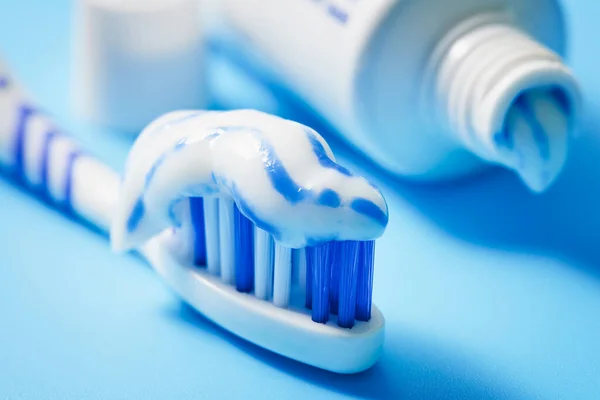 Uygulamalı diş macunu ve açık beyaz arka planda bir tüp macunla diş fırçasının yakın çekimi. İnsan yok. Makro fotoğrafçılık.