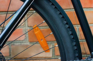 Tekerleklere turuncu plastik yansıtıcı monte edilmiş bisiklet tekerleğinin yakın çekimi. Açık havada..