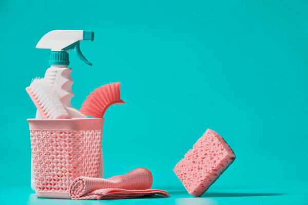 Кисти, губка и бутылка чистящего спрея на зеленом фоне. Услуги по уборке.