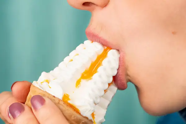 Close-up of the mouth of a Caucasian woman eating an ice cream cone. Side view. Low angle view. Indoors.