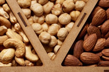 Vitrinde çiğ kaju çekirdeği, fındık ve badem soyulmuş. Üst görünümü kapat.