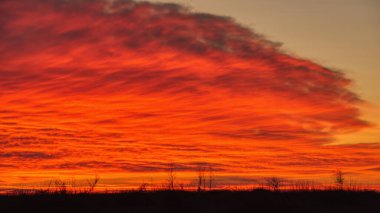 Soğuk mevsimde bulutlu bir gökyüzünde dramatik renkli gün batımı.