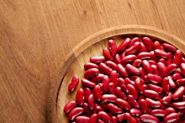 Ahşap bir arka planda, üzerinde fotokopi alanı olan ahşap bir tabakta pişmemiş bir sürü kırmızı fasulye grubu. Üst Manzara. Stüdyo çekimi.