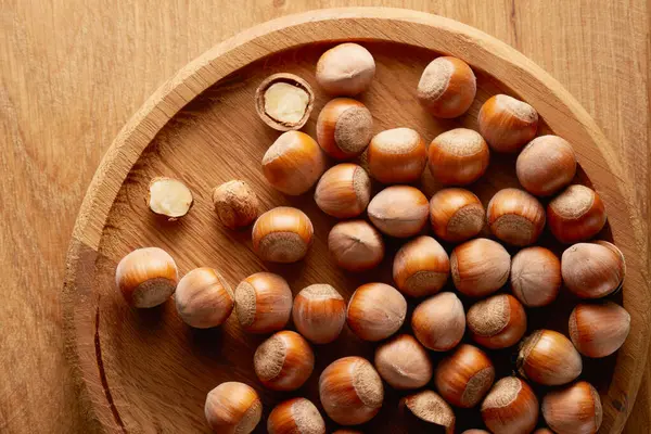Büyük bir grup kabuksuz fındık içeren ahşap bir tabak. Üst Manzara. Stüdyo çekimi.