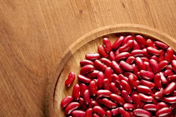 Ahşap bir arka planda, üzerinde fotokopi alanı olan ahşap bir tabakta pişmemiş bir sürü kırmızı fasulye grubu. Üst Manzara. Stüdyo çekimi.