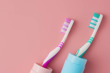 Pembe arka planda iki diş fırçası, üst manzara. Düz yatıyordu.