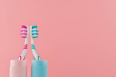 Pembe arka planda seyahat çantasındaki iki diş fırçası fotokopi uzayının düşük açılı görüntüsünden. Stüdyo çekimi.