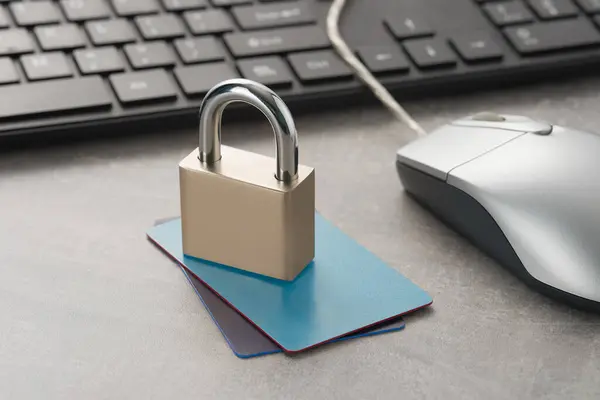 Closed padlock on credit cards and computer mouse and keyboard on the table. Cyber security and protection concept.
