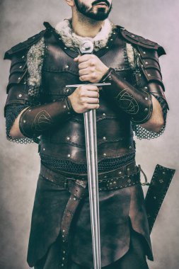 Man in medieval hand made leather costume holding his sword  clipart