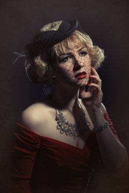 Dantel şapkalı, klasik bir kostüm giymiş kadın.