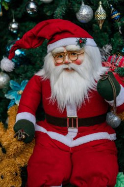 Noel Baba oyuncağı Noel ağacının önünde dünyanın dört bir yanındaki Xmas festivalinde renkli oyuncaklarla süslenmiş.