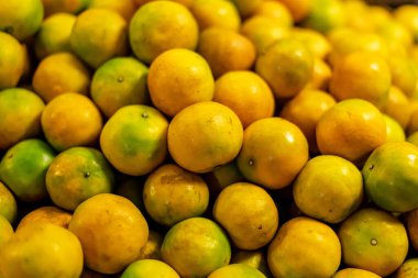 Bangkok 'taki Klong Toey pazarında yeşil-sarı derili olgun portakallar. Turuncu resim arkaplanı