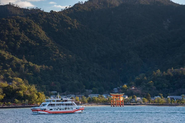 Hiroşima Bölgesi, Japonya - Ocak 02 2019 Miyajima adasına feribottan bakıyoruz. Yüzen kırmızı dev Grand O-Torii kapısı güneşli bir günde, körfez sahilinde duruyor, Hiroşima şehrinde.