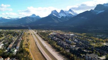 Canmore, Alberta, Canada. Aerial view of Trans-Canada Highway (Highway 1) in a autumn sunny day. The Three Sisters trio of peaks Canadian Rockies mountain range.