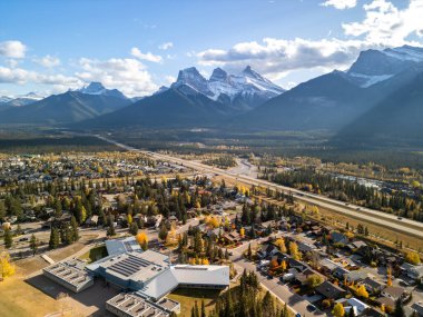 Canmore, Alberta, Canada. Aerial view of Trans-Canada Highway (Highway 1) in a autumn sunny day. The Three Sisters trio of peaks Canadian Rockies mountain range. clipart