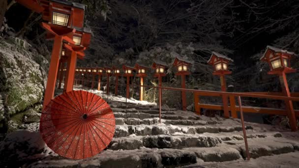 日本の京都の雪 雪の多い冬の夜に伝統的な光の柱を築きました 石の階段に日本の傘 日本文化の概念 — ストック動画
