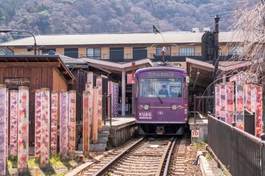 Kyoto, Japonya - 29 Mart 2024: Platformun her iki tarafındaki Kimono orman direkleriyle Arashiyama istasyonunda tren durağı. Keifuku Elektrik Demiryolu tarafından işletilen Arashiyama Hattı.
