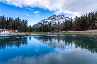 Johnson Gölü 'nün donmuş su yüzeyi kışın. Arka planda karla kaplı Cascade Dağı var. Banff Ulusal Parkı, Kanada Kayalıkları, Alberta, Kanada.