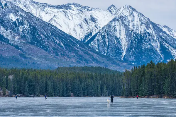 Johnson Gölü 'nde kış zamanı buz pateni yapan turistler. Arka planda karla kaplı dağ. Banff Ulusal Parkı, Kanada Kayalıkları, Alberta, Kanada.