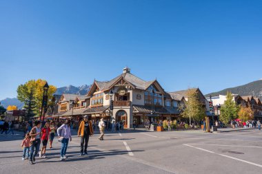 Banff, Alberta, Kanada - Ekim 06 2022: Güneşli bir sonbahar gününde Banff Caddesi 'nde yürüyen turistler.