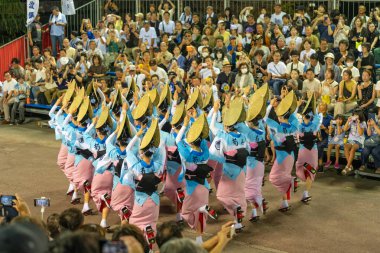 Tokushima Prefecture, Japan - August 14 2024 : Tokushima Awa Odori Festival 2024. Performers wear traditional obon costumes, dance and sing in a formation as they parade through the outdoor stage at night. clipart