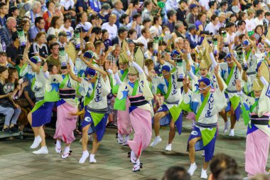 Tokushima Prefecture, Japan - August 14 2024 : Tokushima Awa Odori Festival 2024. Performers wear traditional obon costumes, dance and sing in a formation as they parade through the outdoor stage at night. clipart