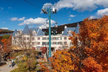 Mont-Tremblant, Quebec, Canada - October 14 2022 : Mont Tremblant Ski Resort autumn maples scenery. Sightseeing by Cabriolet gondola cable car in sunny day. clipart