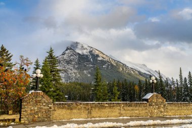 Karla kaplı Rundle Dağı sıradağları. Mavi gökyüzü üzerinde karlı orman ve kışın güneşli bir günde beyaz bulutlar. Banff Ulusal Parkı, Kanada Kayalıkları.