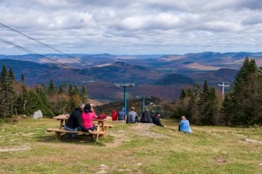 Mont-Tremblant, Quebec, Kanada - Ekim 12021: İnsanlar Mont Tremblant Kayak Tesisi 'nin tepesinden sonbahar manzarasının keyfini çıkarıyorlar. Titrek göl.