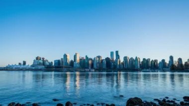 Vancouver şehir merkezi silueti. Renkli binaların ışıkları suya yansıyor. Gün batımından geceye. British Columbia, Kanada.
