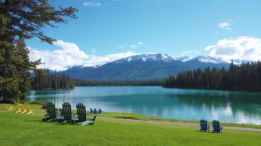 Jasper Ulusal Parkı yaz manzarası, Alberta, Kanada. Beauvert Gölü 'nün (Beauvert Gölü) göl kenarındaki Adirondack sandalyeleri. Arka planda kar tepeli Whistlers Tepesi.