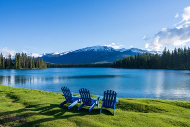 Jasper Ulusal Parkı yaz manzarası, Alberta, Kanada. Beauvert Gölü 'nün (Beauvert Gölü) göl kenarındaki Adirondack sandalyeleri. Arka planda kar tepeli Whistlers Tepesi.