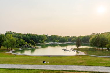 Montreal, Quebec, Canada - August 20 2021 : Mount Royal Park ( Parc du Mont-Royal ) Beaver Lake in summer sunset time. People are relaxing in the park. clipart