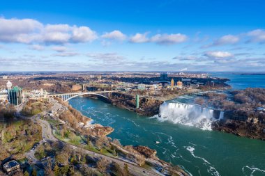 Niagara Falls City, Ontario, Canada - December 19 2021 : Overlooking the Niagara River Rainbow Bridge and American Falls in a sunny day. clipart