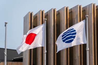 Japon ulusal bayrağı (Nisshoki) ve BIE bayrağı Japonya Pavyonu 'nun dışında 2025 Osaka Kansai Fuarı' nda dalgalanmaktadır. Osaka, Japonya.