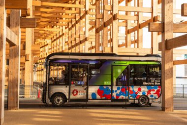 Osaka, Japonya - 30 Nisan 2025: 'E-nakliyeci' EV servis otobüsü hareket halinde, ziyaretçileri Dünya Fuarı 2025 sahasında naklediyor.