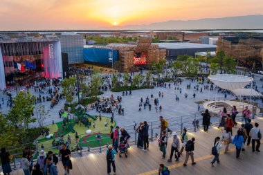 Osaka, Japonya - 30 Nisan 2025 Grand Ring geçidinde ziyaretçiler 2025 Dünya Fuarı 'nda güzel altın gün batımını yakalıyorlar..