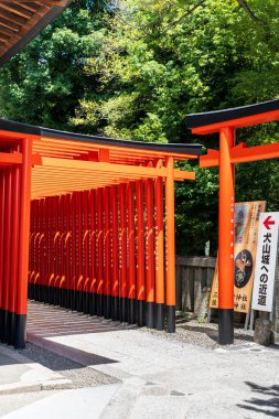 Inuyama, Aichi, Japonya - 22 Temmuz 2024: Inuyama Kalesi 'ne giden ünlü bir yol olan Sanko Inari Tapınağı' nın canlı kırmızı torii kapıları tüneli.
