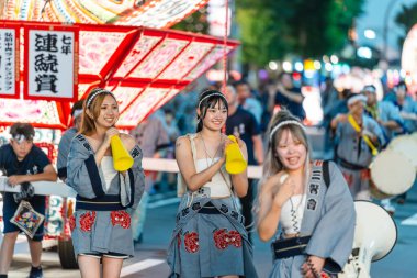 Hirosaki, Aomori, Japonya - 5 Ağustos 2024: Geleneksel Japon elbiseli neşeli genç kadınlar Neputa Festivali geçit töreninin canlı atmosferinin keyfini çıkarıyorlar.