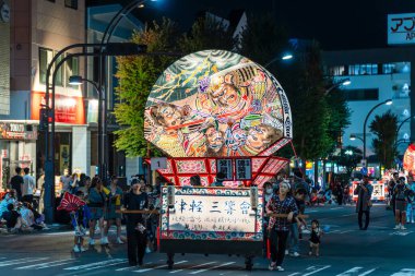 Hirosaki, Aomori, Japonya - 5 Ağustos 2024: Hirosaki Neputa Festivali. Uçsuz bucaksız ve aydınlık hayran şekilli Neputa şamandırası bir müzik grubuyla birlikte sokaklarda süzülüyor..