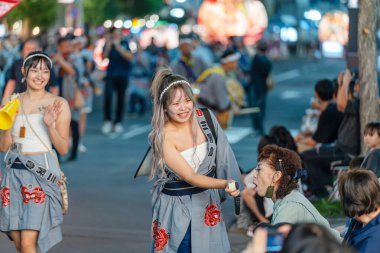 Hirosaki, Aomori, Japonya - 5 Ağustos 2024: Geleneksel Japon elbiseli neşeli genç kadınlar Neputa Festivali geçit töreninin canlı atmosferinin keyfini çıkarıyorlar.