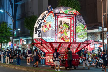 Hirosaki, Aomori, Japonya - 5 Ağustos 2024: Hirosaki Neputa Festivali. Uçsuz bucaksız ve aydınlık hayran şekilli Neputa şamandırası bir müzik grubuyla birlikte sokaklarda süzülüyor..