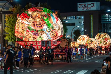 Hirosaki, Aomori, Japonya - 5 Ağustos 2024: Hirosaki Neputa Festivali. Uçsuz bucaksız ve aydınlık hayran şekilli Neputa şamandırası bir müzik grubuyla birlikte sokaklarda süzülüyor..